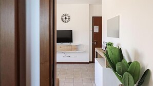 Ein modernes Wohnzimmer mit Fernseher, einer Uhr und einer großen Pflanze.