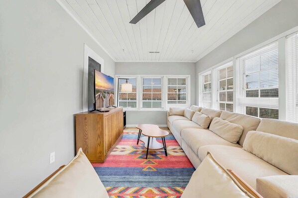 A living room with a sofa, a coffee table, a TV, and a colorful rug.