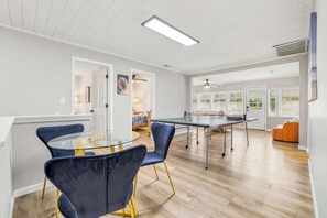 A dining area with a glass-top table, blue chairs, and a wooden floor.
