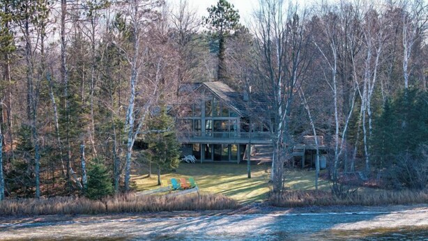 A lakeside cabin with a deck and outdoor seating. - Loon Song on Lost Land Lake | Access to Teal Lake | Trophy Musky Fishing (Hayward)