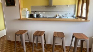 Una cucina con un ampio specchio, quattro sgabelli e un pavimento piastrellato.