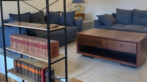 Un soggiorno con divano, tavolino, libreria e lampada.