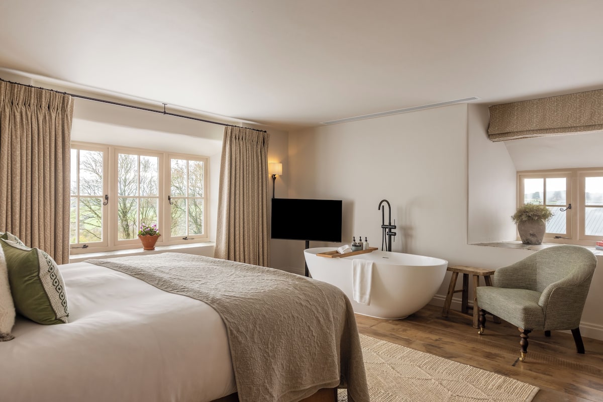 Ein Schlafzimmer mit einem großen Bett, einer Badewanne, einem Sessel und einem Fernseher.