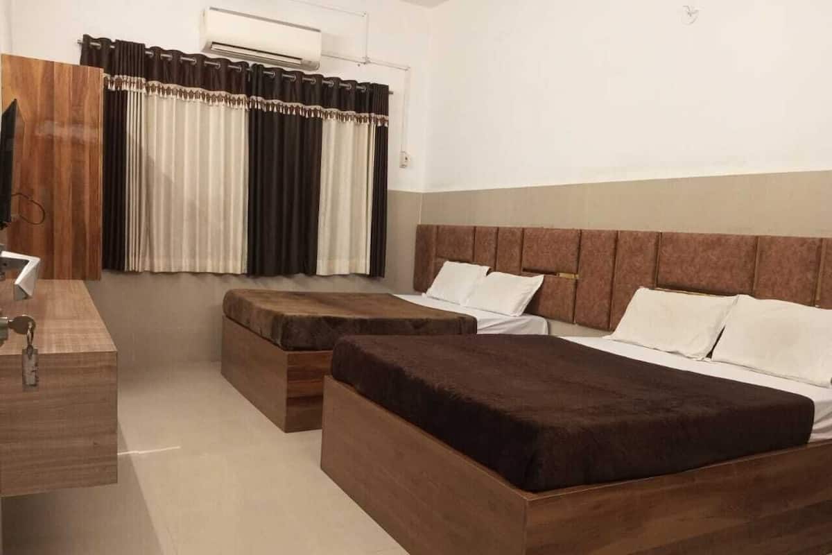 A bedroom with two beds, a wooden dresser, and a window with curtains.