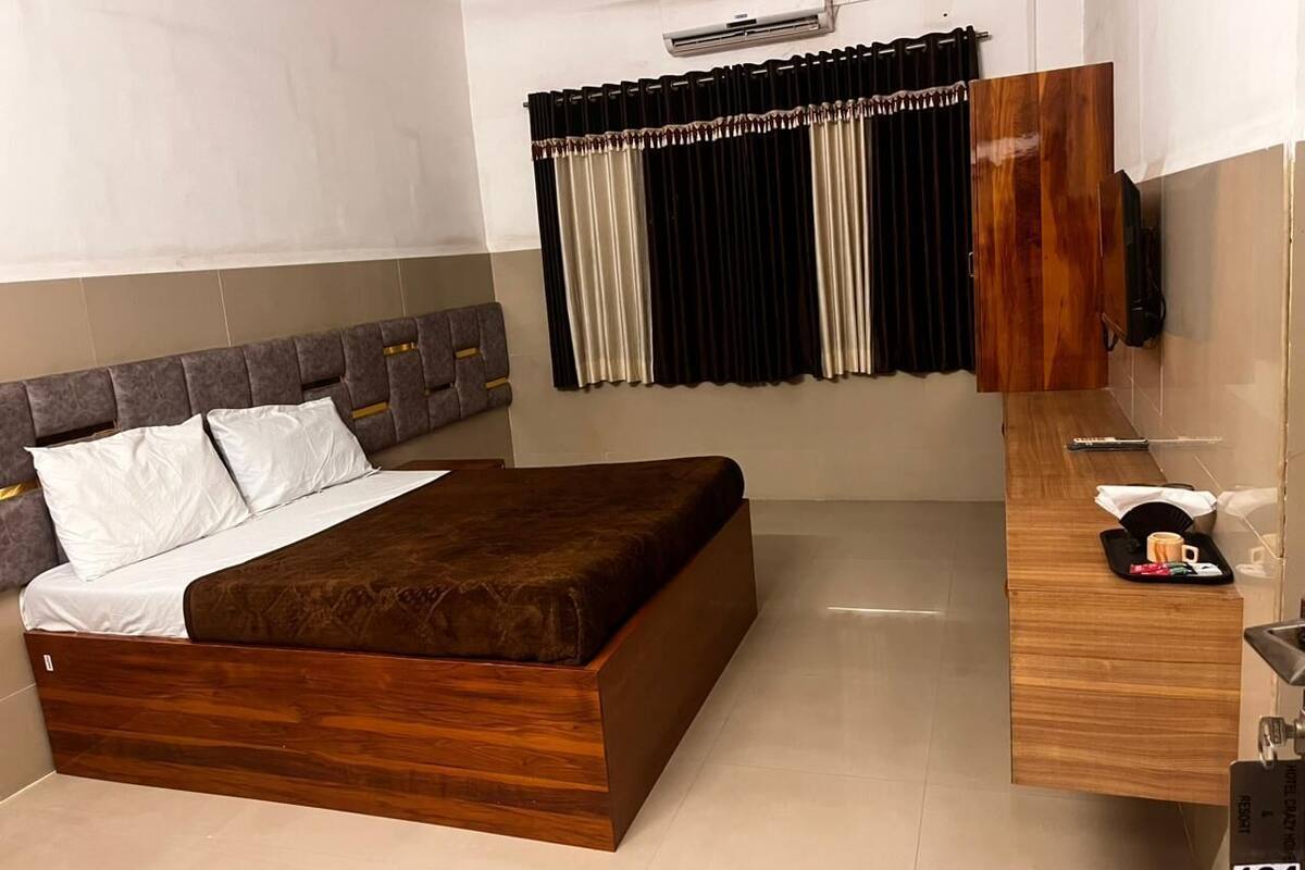 A modern hotel room with a wooden bed, a built-in desk, and a large mirror.