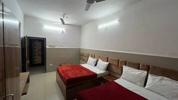 Habitación de hotel con dos camas, cabecero de madera, manta roja y ventiladores de techo.