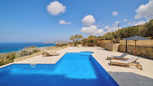 Une piscine rectangulaire agrémentée de deux chaises longues et d’une pergola.