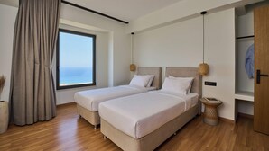 Une chambre d’hôtel moderne avec deux lits, une grande fenêtre offrant une belle vue, un plancher en bois et une petite table d’appoint.