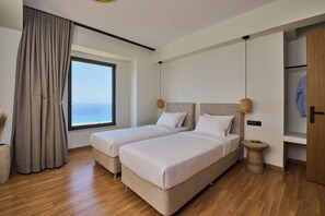 Une chambre d’hôtel moderne avec deux lits, une grande fenêtre offrant une belle vue, un plancher en bois et une petite table d’appoint.