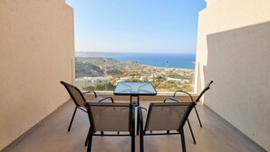 Un balcon agrémenté d’une table et de chaises, offrant une vue sur la mer et le paysage environnant.