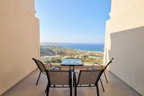 Un balcon agrémenté d’une table et de chaises, offrant une vue sur la mer et le paysage environnant.