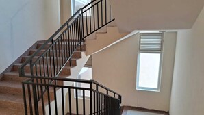 A staircase with black railings leading to an upper floor. - OMAXE DG HOMESTAY (prayagraj)