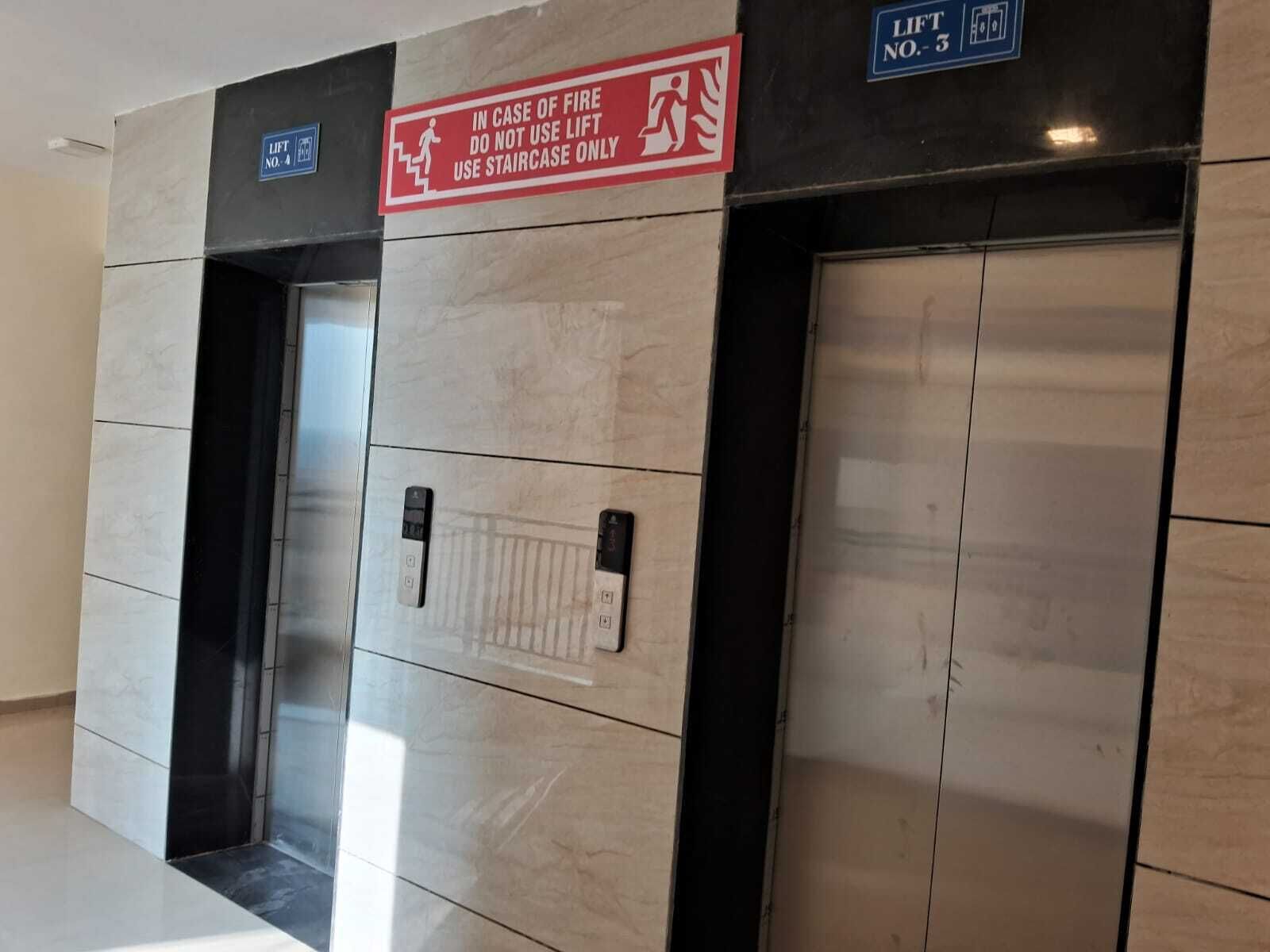 An elevator with a sign instructing to use the stairs in case of fire.