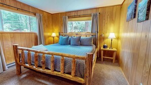 Una habitación con paneles de madera, una cama, dos lámparas de noche y una ventana.