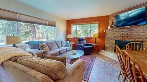 Una sala de estar con sofá, sillón, mesa de centro y chimenea.