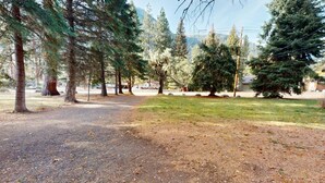 A park with a dirt path, trees, and a grassy area. - Cozy Frances Lake Retreat | Wallowa Lake Fun (Joseph)