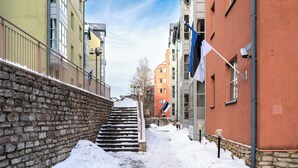 Ein schmaler, mit Schnee bedeckter Weg zwischen Gebäuden mit Steinmauern und Balkonen.