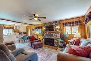 A cozy living room with a fireplace, a dining area, and a kitchen.