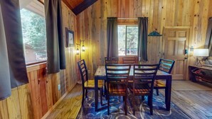 Un interno in legno con un tavolo da pranzo, sedie, un tappeto e una porta.