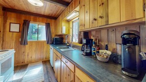 Interno di una casetta in legno con angolo cottura, comprensivo di fornello, forno a microonde, macchina da caffè e caffettiera.