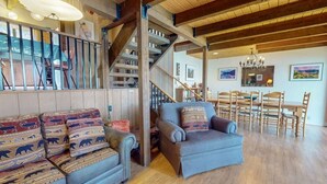 Una sala acogedora con un sofá, una silla, una mesa de comedor y una escalera.