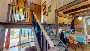 Un interior de madera con escalera, comedor y ventanas amplias.