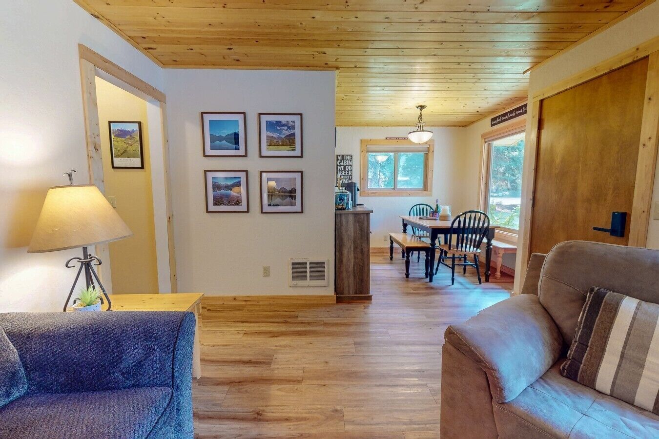 A cozy cabin interior with a dining area, a sofa, and a lamp.