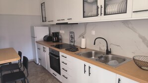 A modern kitchen with white cabinets, a wooden countertop, a stainless steel sink, and a coffee maker. - Casa Dili Stylish 2BR Apartment (Athens)