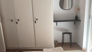A bedroom with a bed, a wardrobe, a mirror, a small stool, and a shelf. - Casa Dili Stylish 2BR Apartment (Athens)