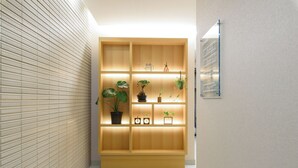 A hallway with a wooden display unit featuring potted plants and a mirror. - oyado shinmachi gojo (Kyoto)