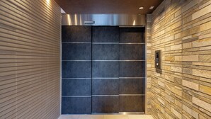 A modern elevator with a metallic finish and a control panel on the wall. - oyado shinmachi gojo (Kyoto)