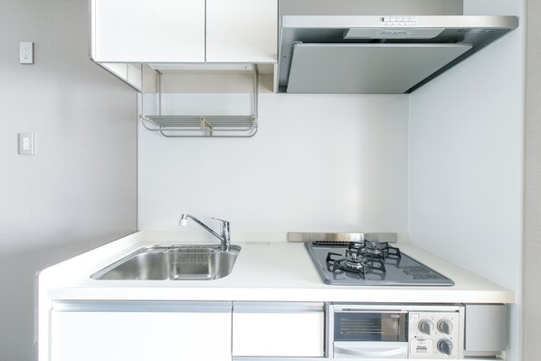 A compact kitchen with a sink, stove, and built-in oven. - oyado shinmachi gojo (Kyoto)