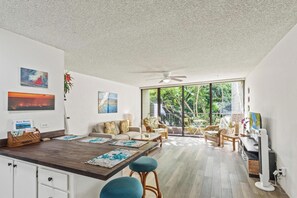 Ein modernes Wohnzimmer mit Essbereich, großen Fenstern und einem Deckenventilator.