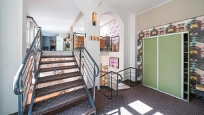 A staircase with a metal railing leading to a room with a patterned wall and a green wardrobe. - Design Apartments - Remise Blumberg (Potsdam)
