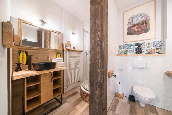 Une salle de bain moderne avec un meuble-lavabo en bois, un grand miroir, une douche et des toilettes.