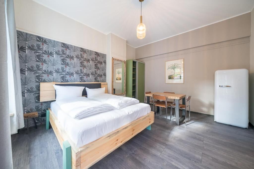 A bedroom with a wooden bed, a desk, and a refrigerator.