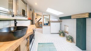 A modern kitchen with a large black bowl on the counter, white tiled walls, and a skylight above. - Design Apartments - Remise Blumberg (Potsdam)