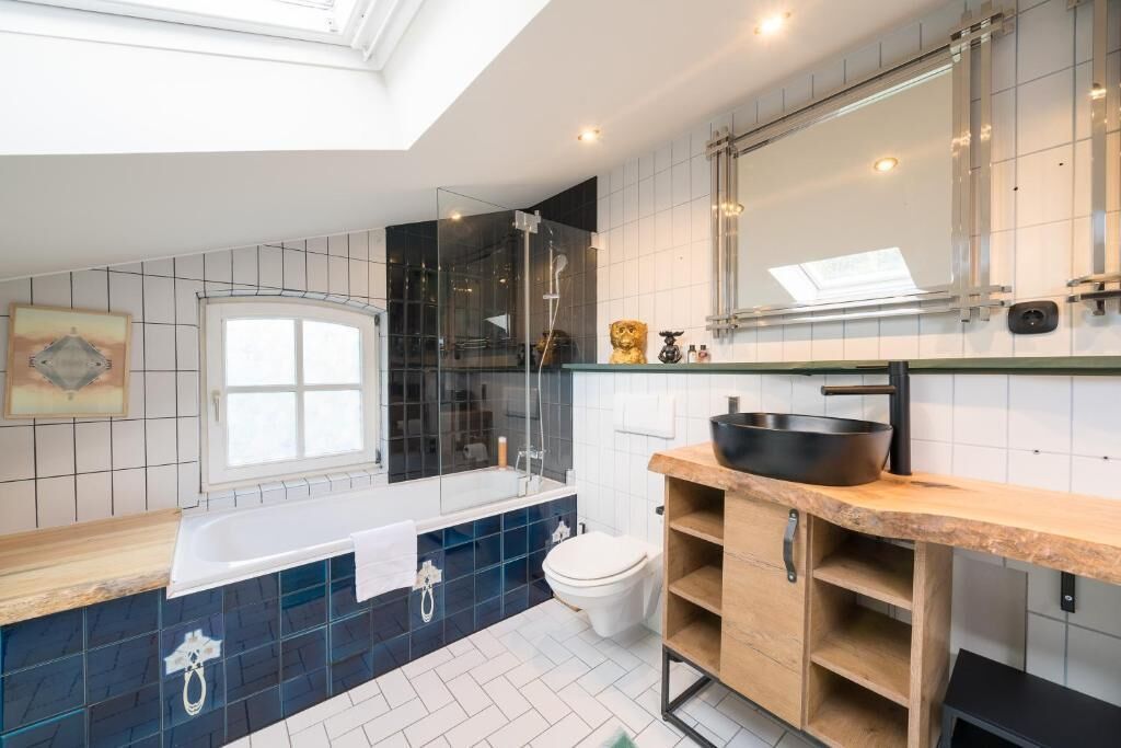 Un bagno moderno con doccia vetrata, uno specchio grande e un mobile vanitario in legno.