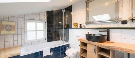 Un bagno moderno con doccia vetrata, uno specchio grande e un mobile vanitario in legno.