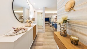 Ein modernes Interieur mit Holzboden, einem weißen Empfangsschalter, einem Spiegel und einer Wanddekoration mit Ventilator und Blumen.