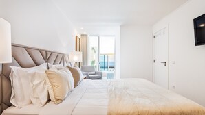 Ein Hotelzimmer mit einem großen Bett, einem Sessel, einem Fernseher und Blick ins Freie.