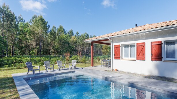 Une piscine avec des chaises et un espace patio couvert.