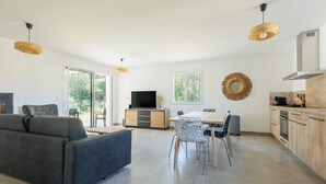 Un salon moderne comprenant un canapé, une table à manger, des chaises et un téléviseur.