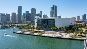 A modern building with a large sign reading 'Kaseya Center' by a waterfront with palm trees and a marina. - Condo First Downtown Miami (Miami)