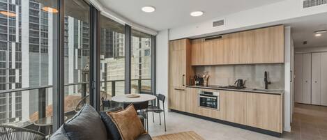 Una cocina moderna con armarios de madera, un comedor con mesa y sillas redondas, y una sala de estar con sofá y mesa de centro.
