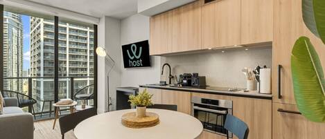 A modern kitchen with wooden cabinets, a Bosch oven, and a dining area with a round table and chairs.