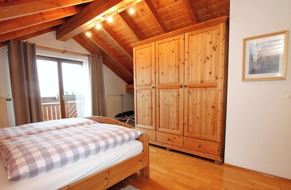 Una camera da letto con un letto di legno, un ampio armadio e un balcone.