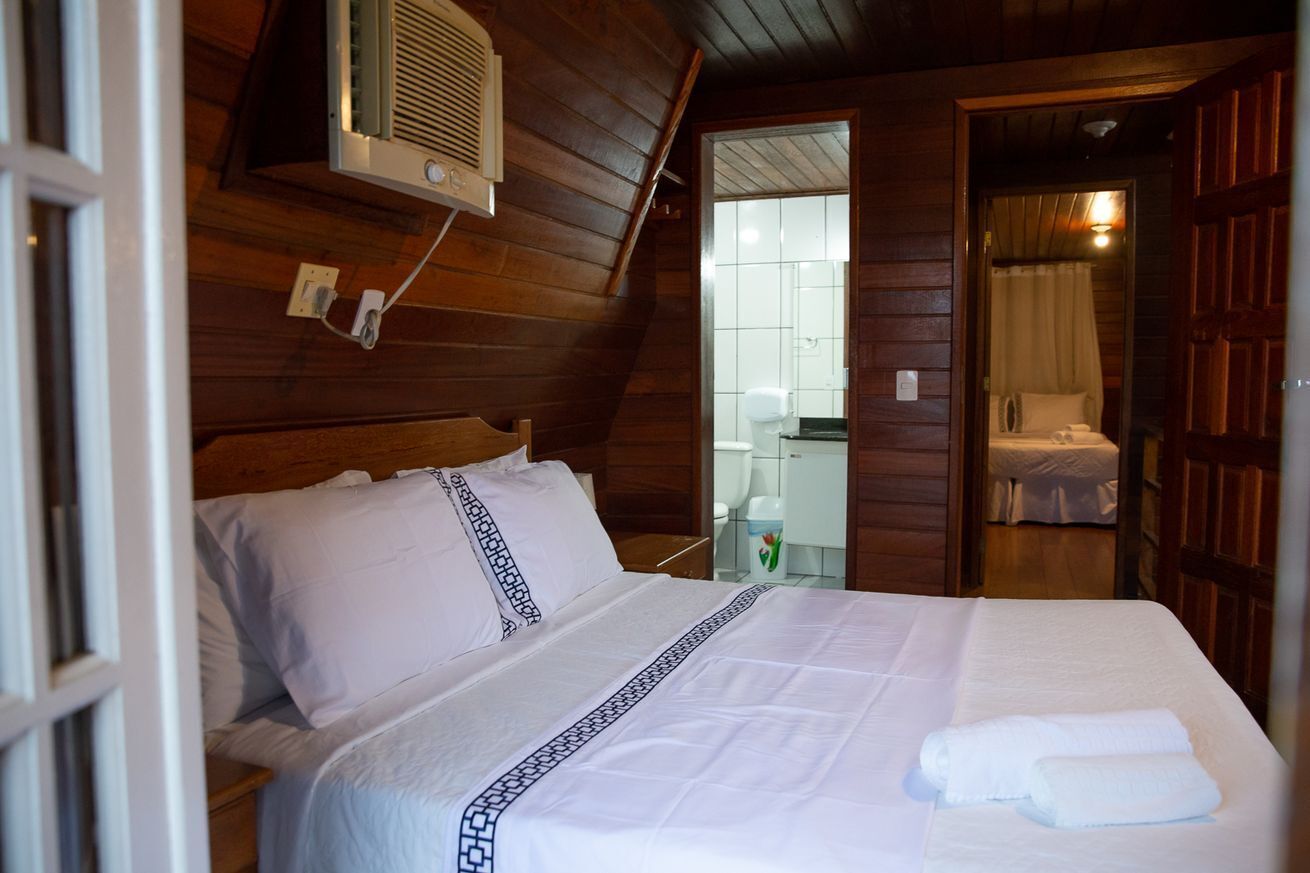 A wooden-paneled room with a bed, a mirror, and a bathroom visible through an open door.