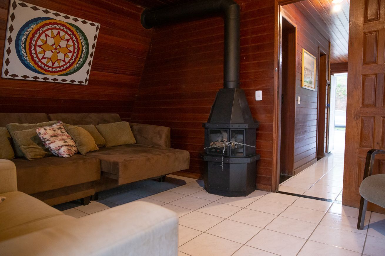 A cozy room with a wooden interior, a sofa, a fireplace, and a door leading to another room.