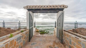 A stone pathway leading to a beach entrance with a pergola overhead. - Beach Access Apt in Playa Real | Pool & Terrace - Pass the Keys (Marbella)